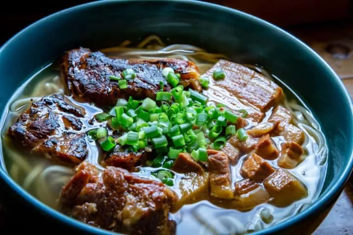 Semangkuk Okinawa Soba dengan daging babi di atasnya.